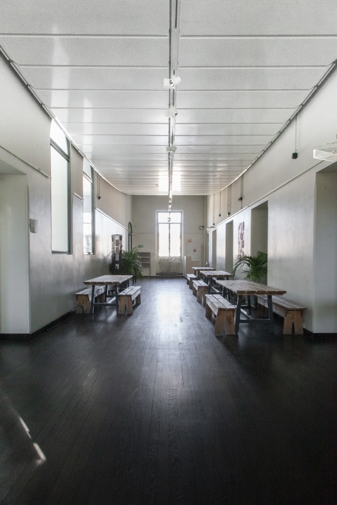 C'est une photo du foyer du 2e éltage. Le foyer est un couloir très lumineux. Il y a des bancs et des tables en bois.