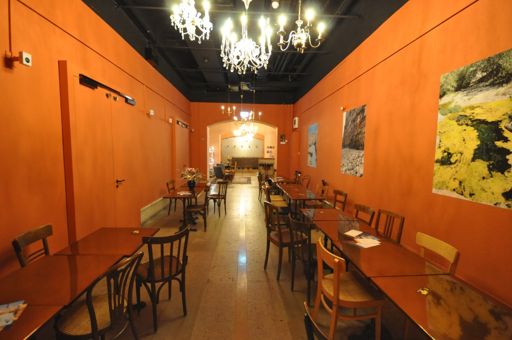 C'est une photo du foyer du sous-sol. Il y a des chaises en bois et des lustres. Les parrois sont oranges.