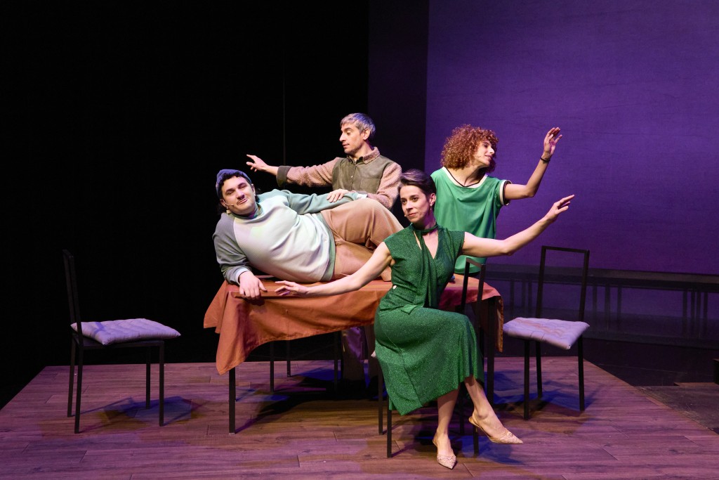 C'est une photo des protagonistes du spectacle. En premier plan la maman Lisa Tatin avec une robe verte, sur la table le fils, Loic Valley, à droite du fils, la fille avec un t-shirt vert et tout derriere le papa.