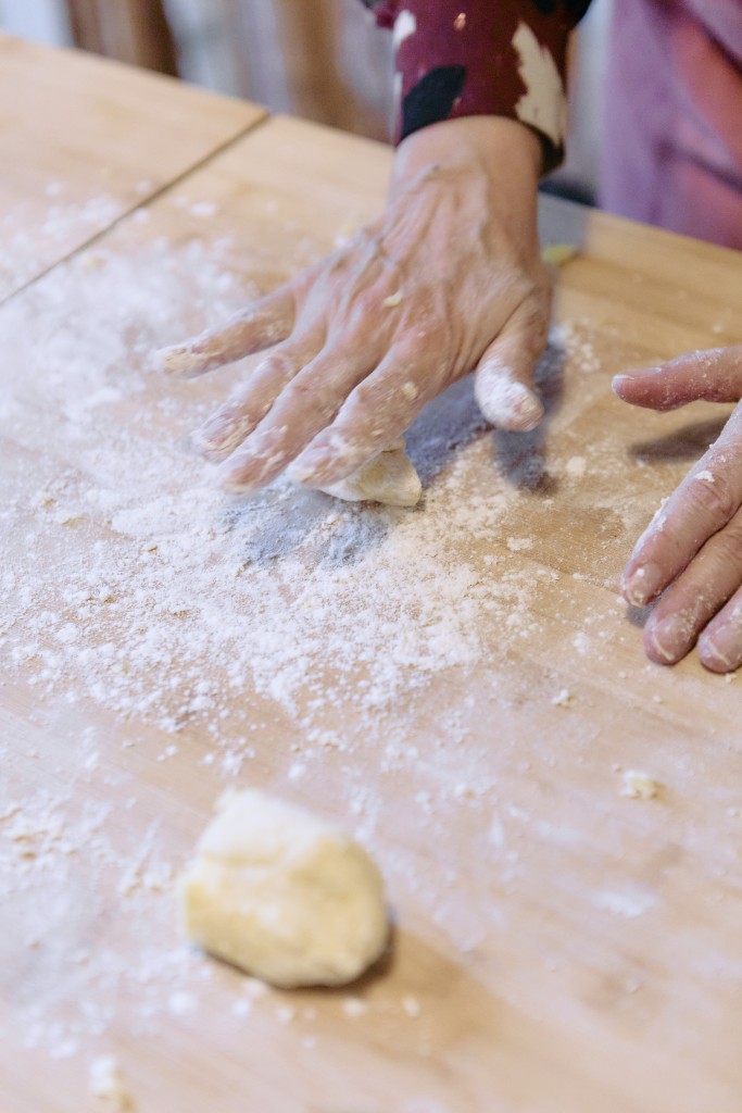 On voit deux mains en train de travailler une pâte comme une pate à pizza ou une pâte pour des pâtes fraiches.