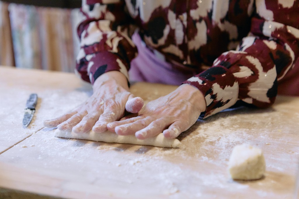 Ce sont deux main en train de travailler de la patte à forme de petit boudin. Il y a de la farine sur le plan de travail.