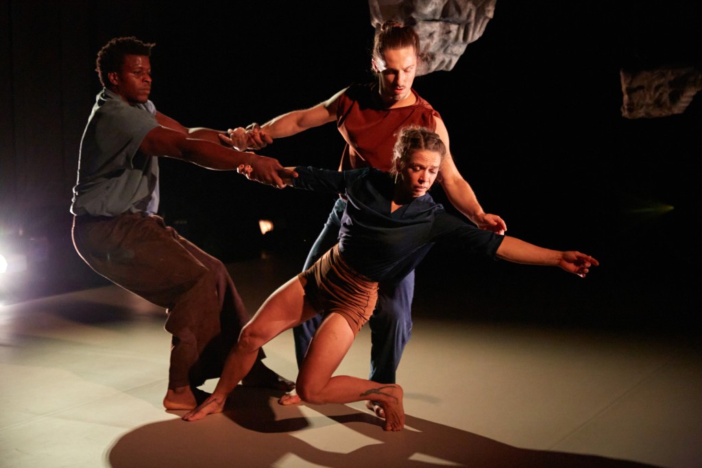 Trois personnes sur scène en train de danser elles se tiennent les bras comme pour rester en équilibre.