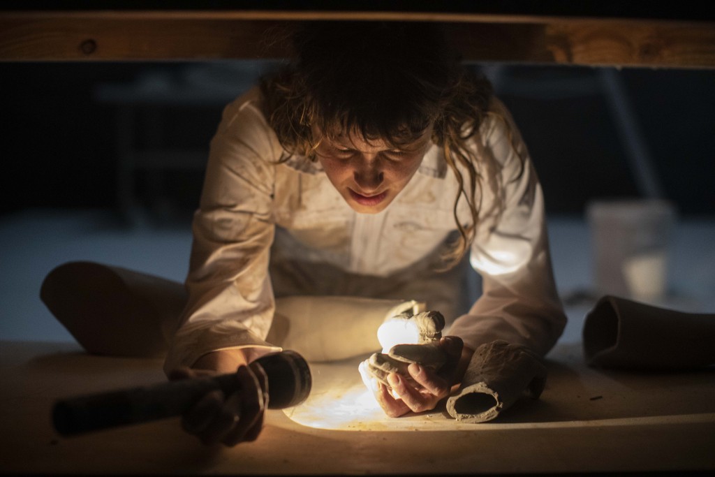 Une personne observe des morceaux à la lampe de poche. On ne sait pas trop s'il s'agit de morceau de statue ou de cailloux.