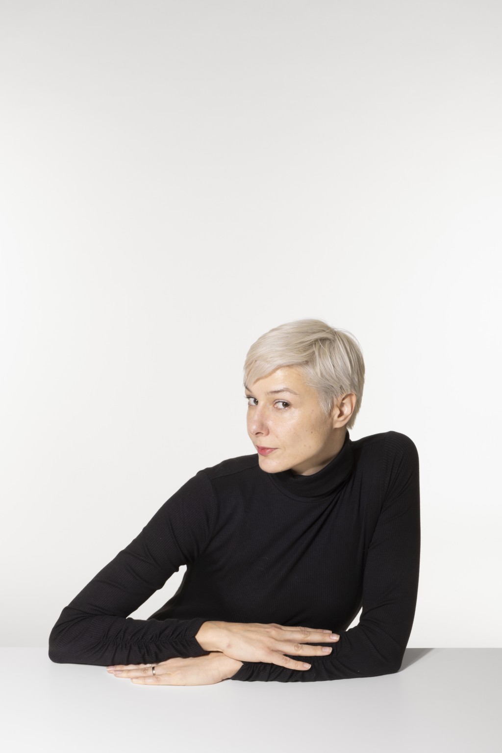 Photo de Danica Hanz l'auteure. Elle a les cheveux blonds courte et elle porte un pull noir col roulé