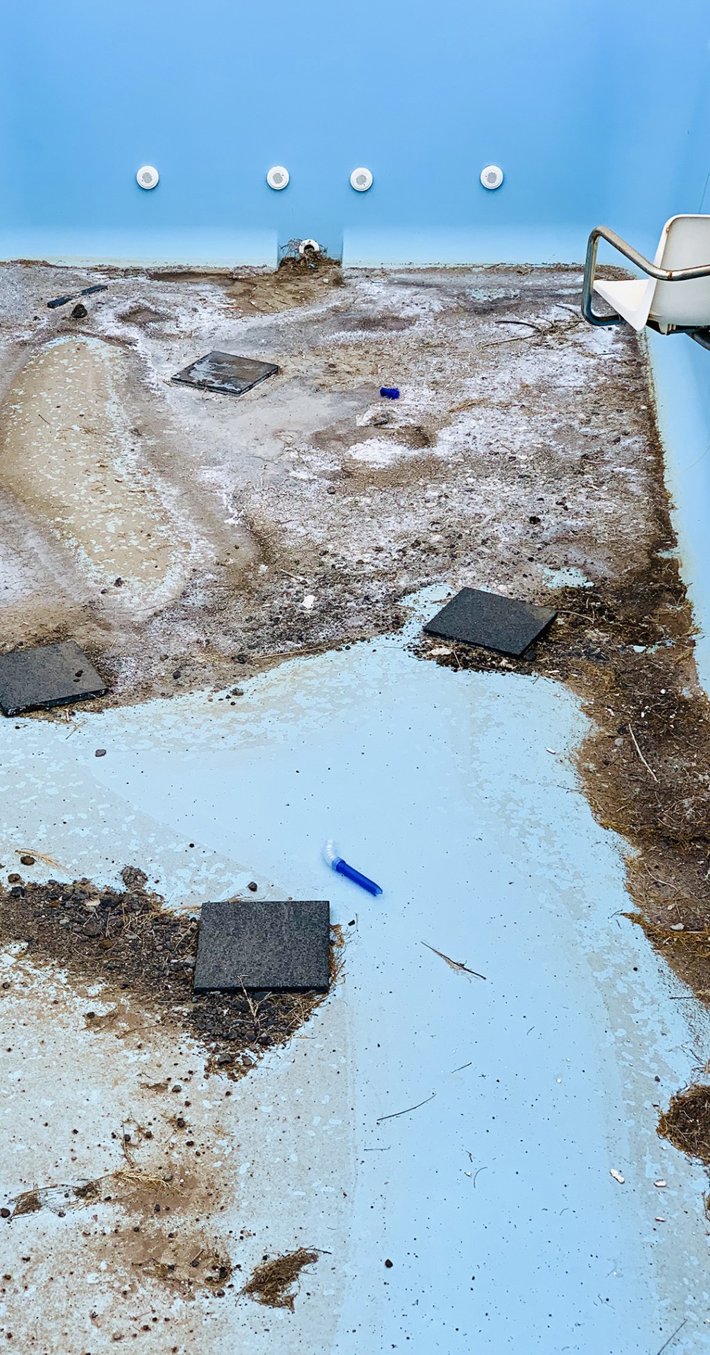 C'est la photo du fond d'une piscine vide et abandonné. Sur ce fond on dirait qu'il y a aussi des ojtes qui ont été jetés.