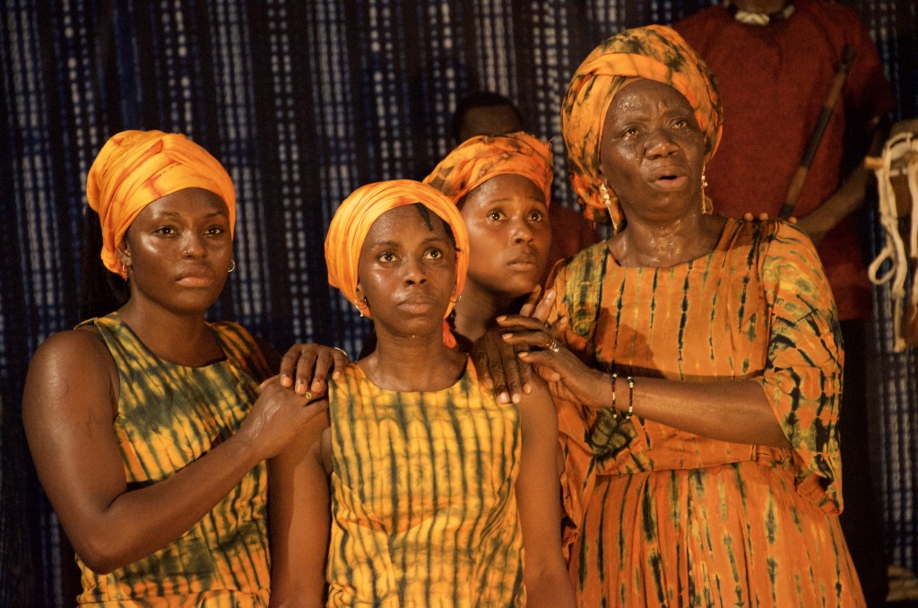 Quatre personnes habillées avec des vetements typiques africains avec turbant et aux couleurs jaune/orange. Elles ont l'air triste, inquiete et pensive