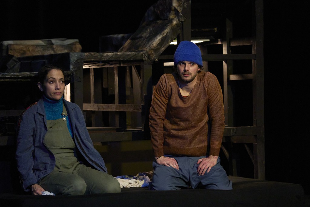Dans cette photo à gauche la comédienne Verana Lopes et à droite le comedien Simon La Barriere. les deux sont assis par terre et la photo est assez sombre. Les deux ont le regard en coin.