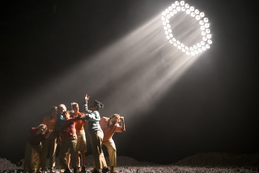 Un groupe de personne illuminé par un exagone de projecteurs depuis le haut. Il s'agit d'une photo du spectacle Augustin à la mine.
