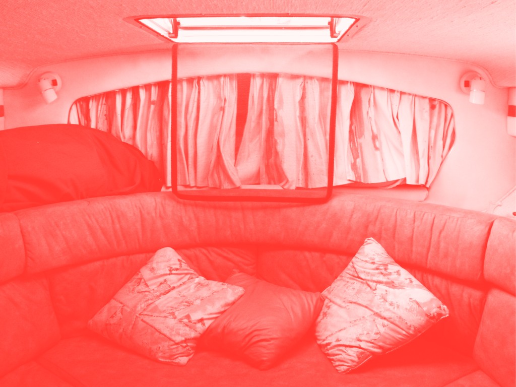 L'intérieur d'un van. On voit comme un canapé et des coussins. La photo est en filtre couleur.