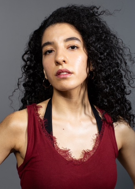C'est la photo de Kenza Zourdani elle porte une t-shirt rouge elle a les cheveux longs noir et bouclés.