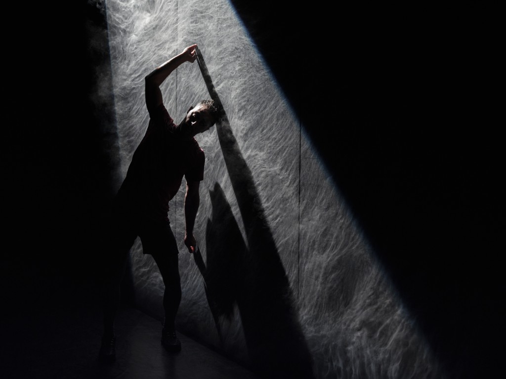 C'est la silhouette d'une personne qui se penche vers le mur en appuyant ses mains au mur. Mais la photo est très sombre.