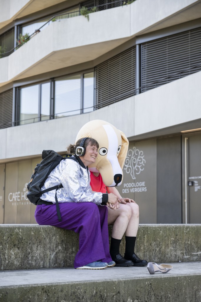 Une personne avec un casque à côtés d'une autre personne avec un gros masque de chien.